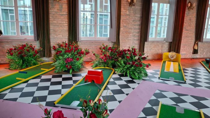 Minigolfbahnen auf Schachbrettboden in einem mit Rosen dekorierten Saal