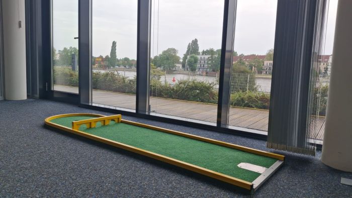 Minigolfbahn vor einer Fensterfront mit Blick aufs Wasser