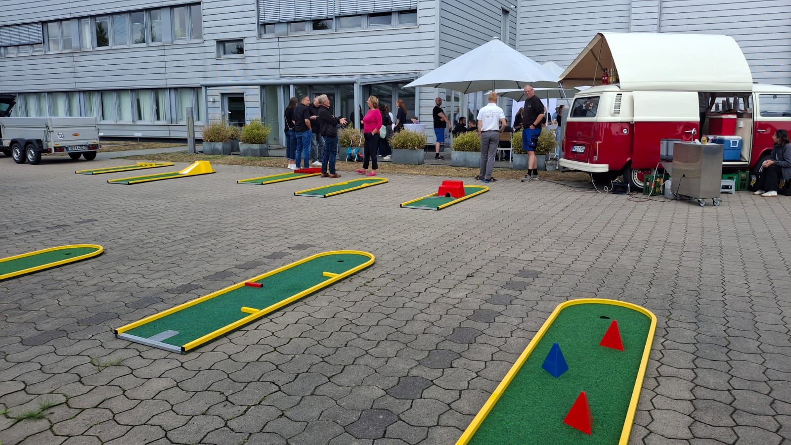 Minigolfbahnen auf dem gepflasterten Hof eines Firmengeländes bei einem Betriebsfest