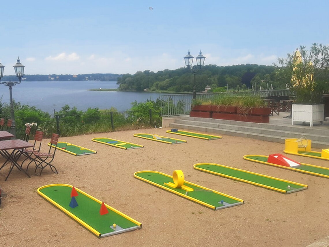 Mehrere komplette mobile Minigolfbahnen auf einer Terrasse am Seeufer